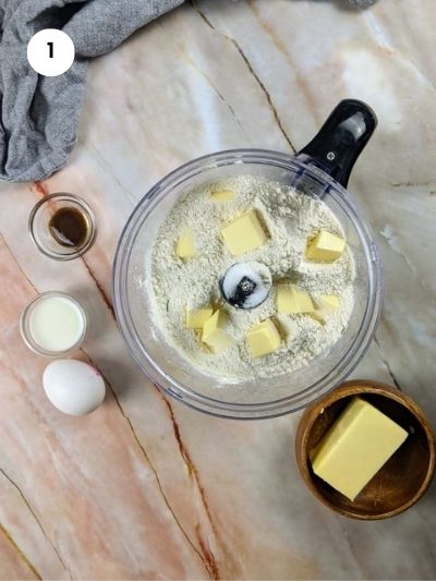 Adding the flour, sugar and butter cubes to the food processor.