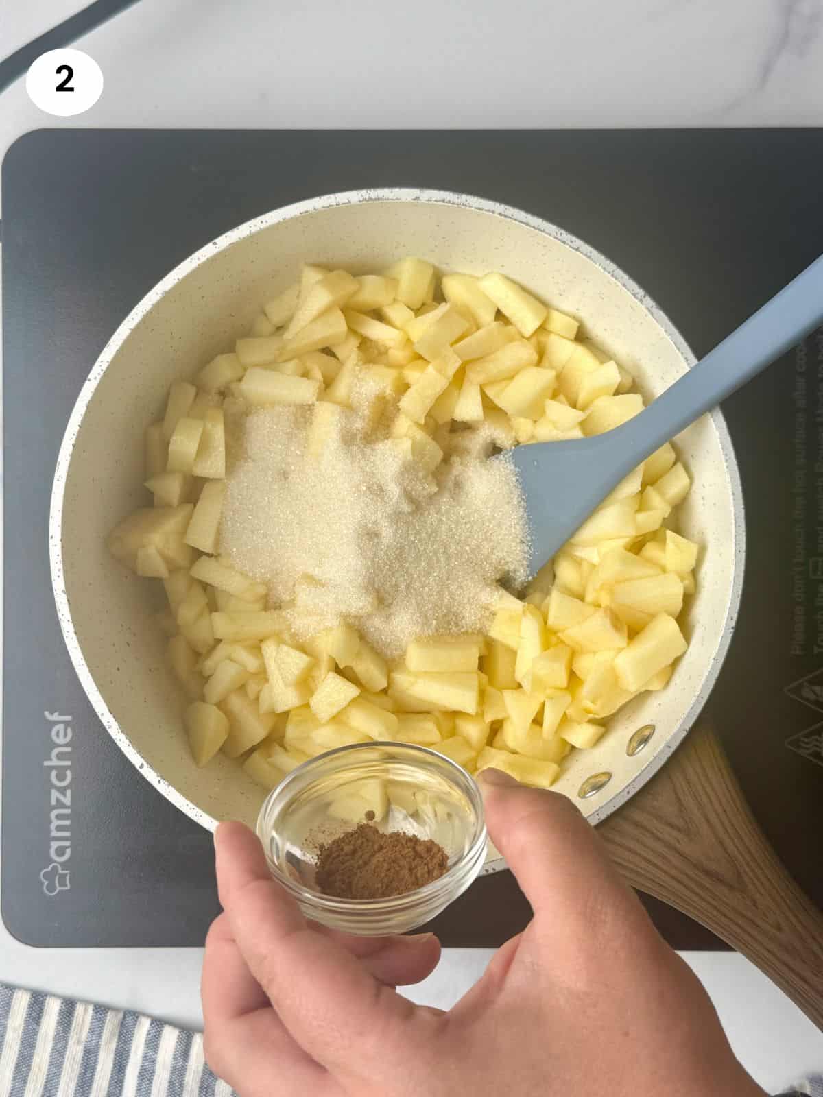 Adding sugar and cinnamon to the pot with the apples.