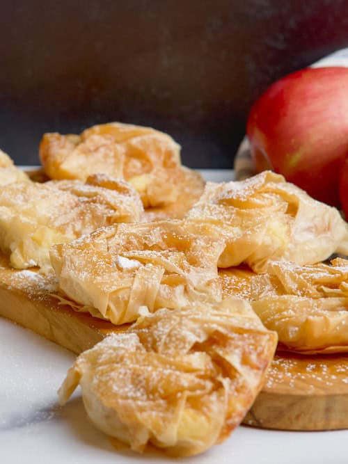 Phyllo pastries with dusted powdered sugar on top of wooden board.