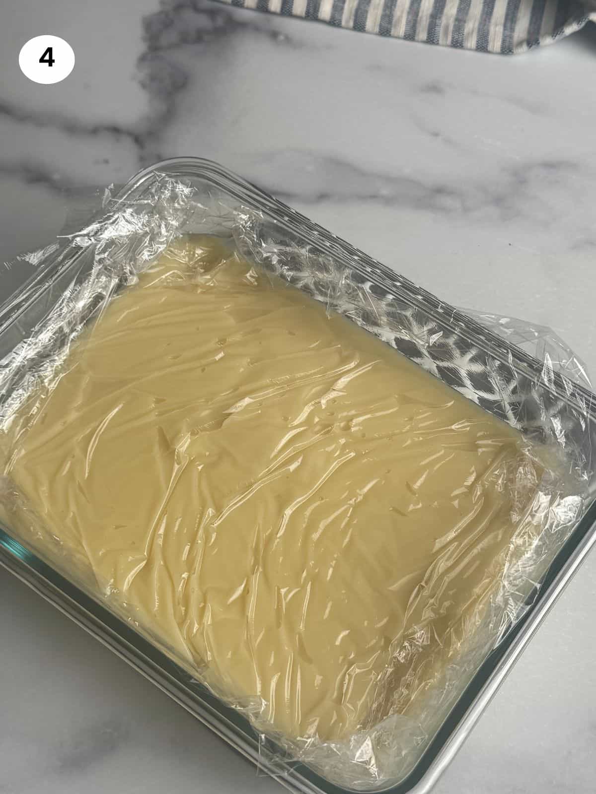 Custard in glass bowl with cling film on top to cool down.