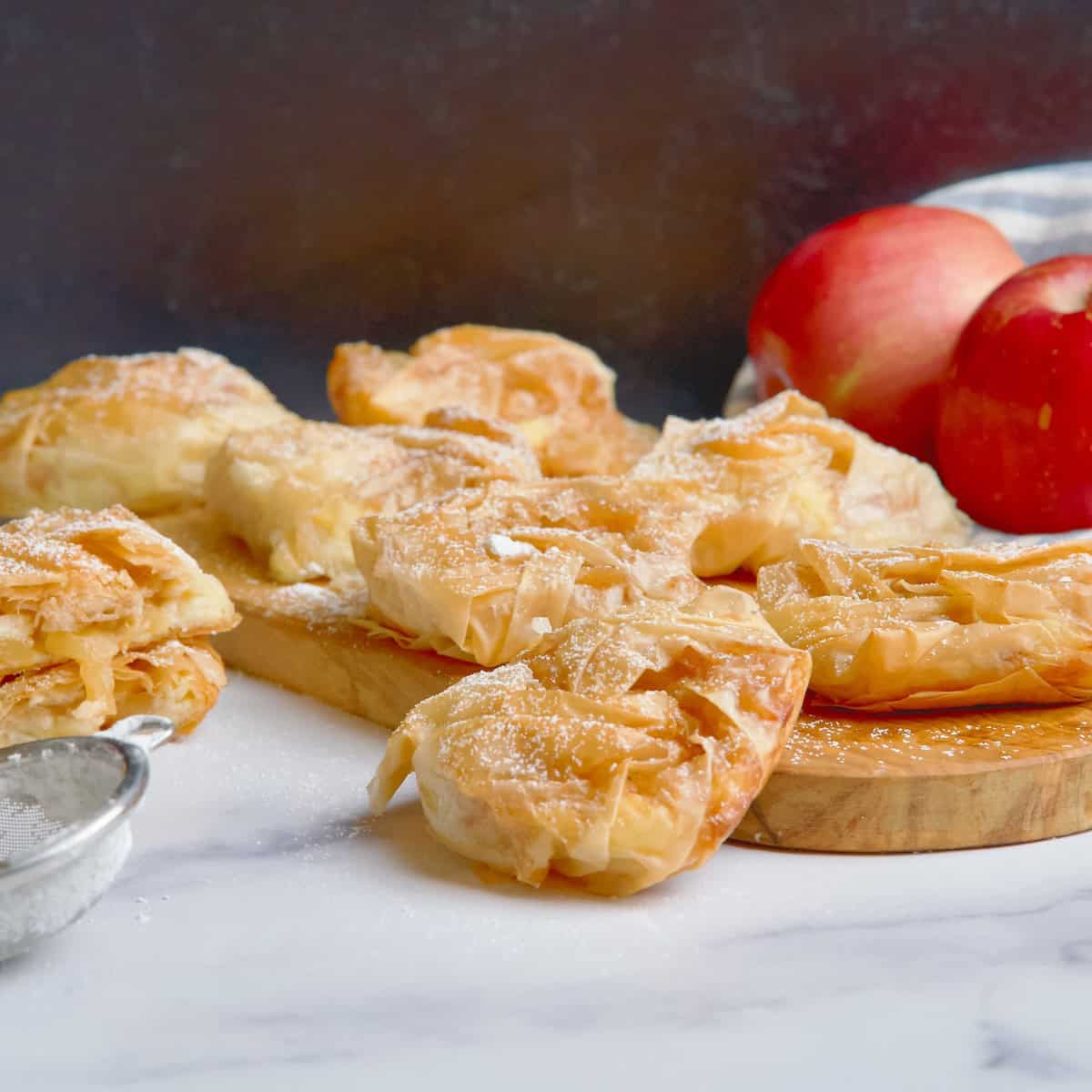 Phyllo pastries with dusted powdered sugar on top of wooden board.