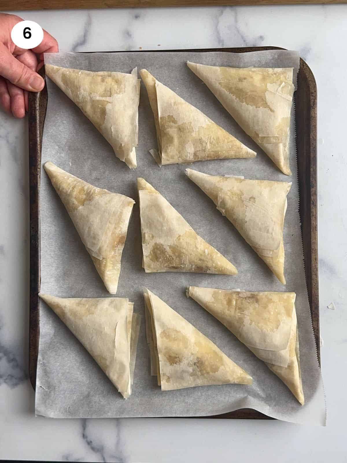 Apple turnovers on a lined baking tray ready for the oven.