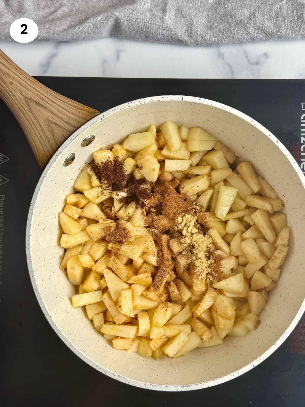Cooking the apples with the sugar and spices in a pot.