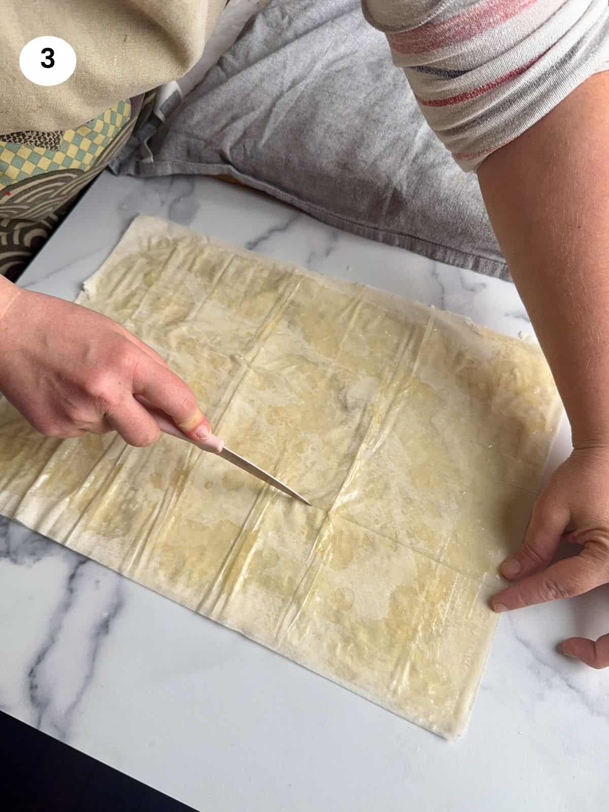 Cutting the phyllo dough into long strips.