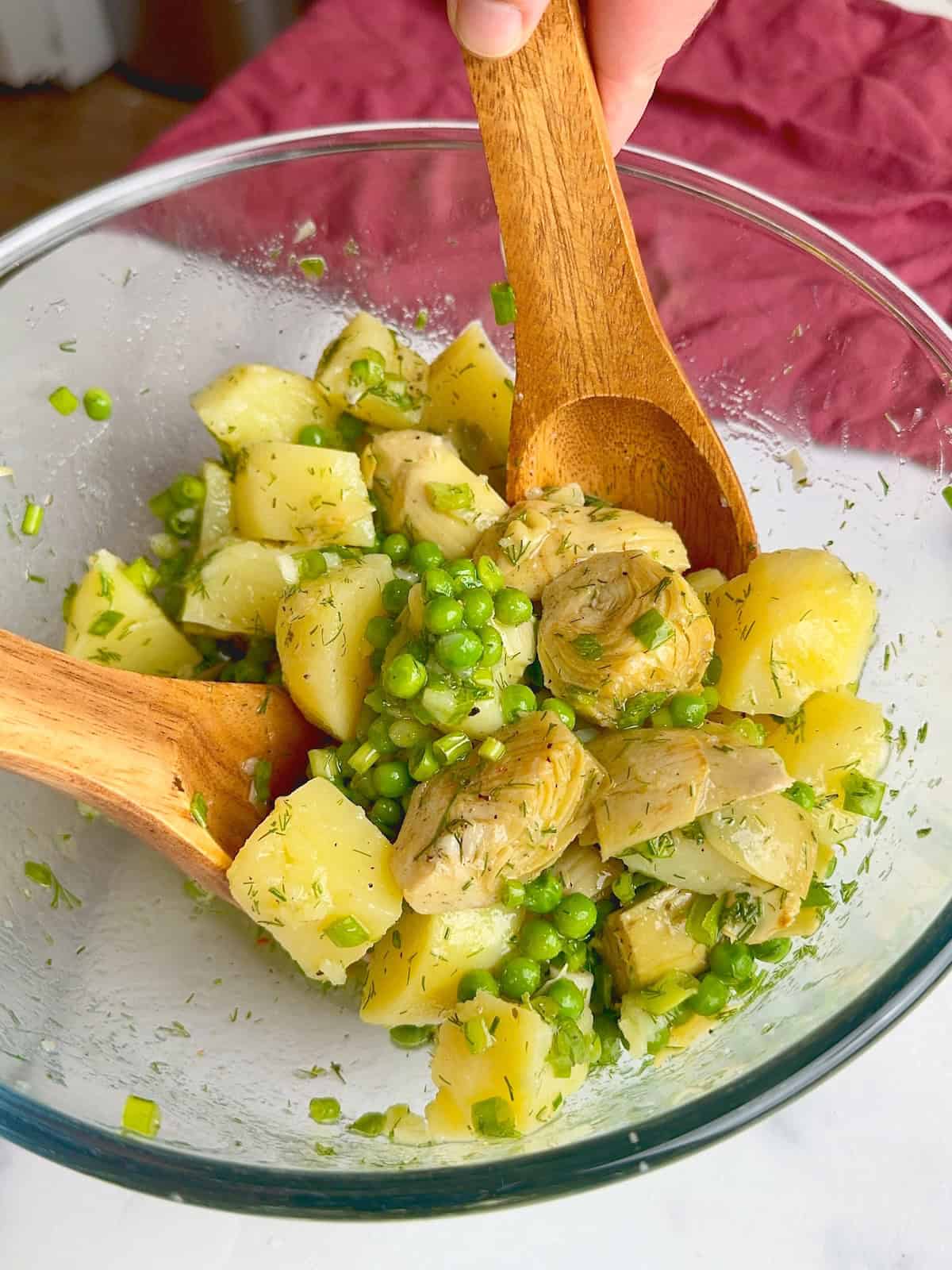 Mixing the artichoke and potato salad.