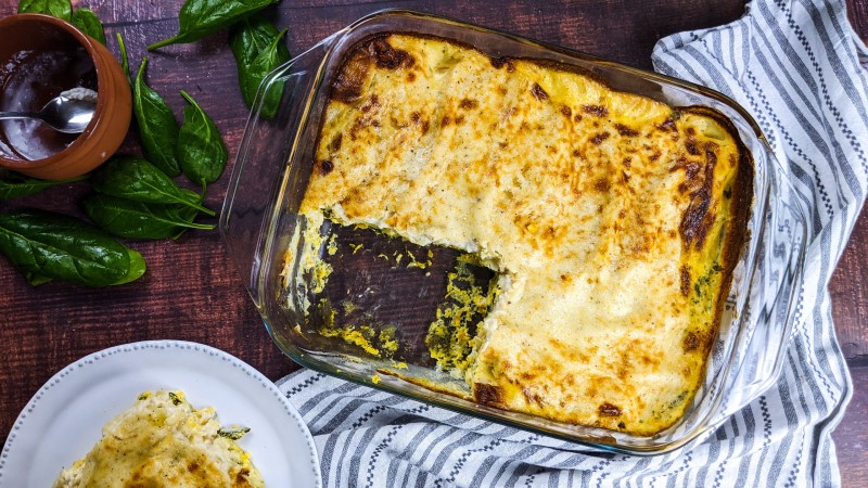 Baked cannelloni in a tray with a piece served in white plate.