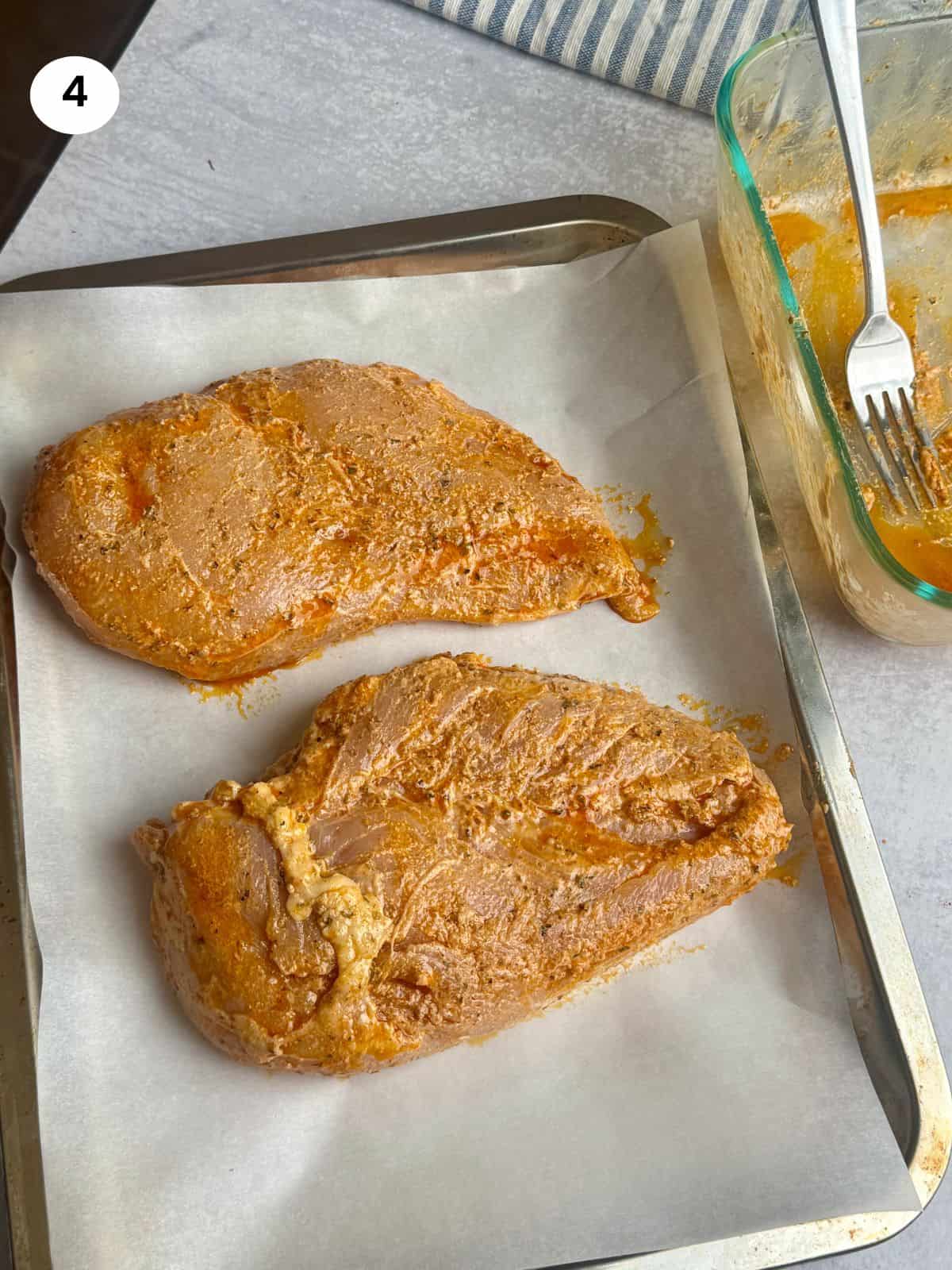 Chicken breasts on a tray ready to go in the oven.