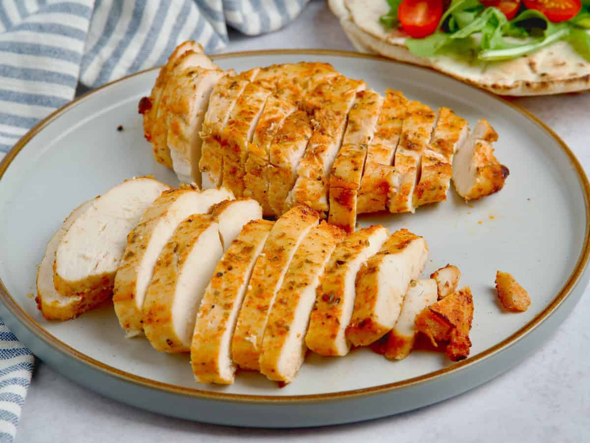 Chicken breasts with rubbed spices cut into slices and served on a plate.