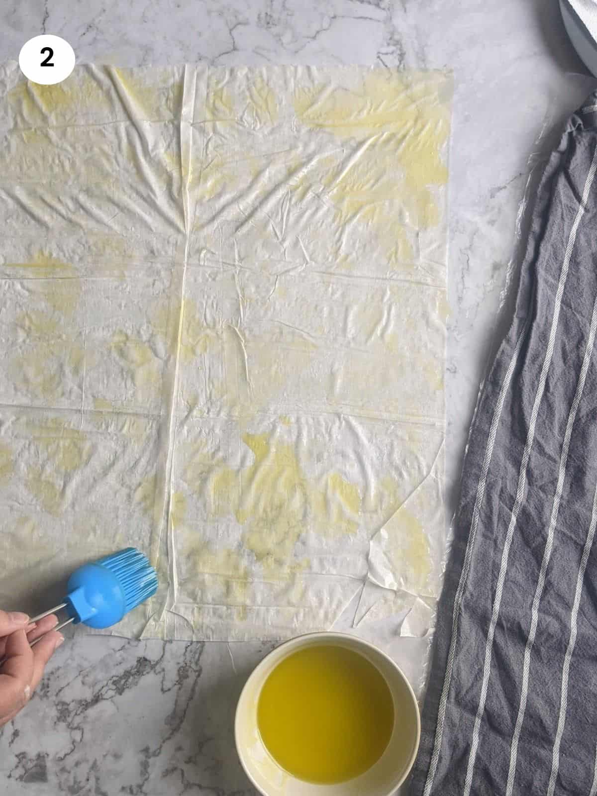 Brushing the first layer of phyllo dough with oil.