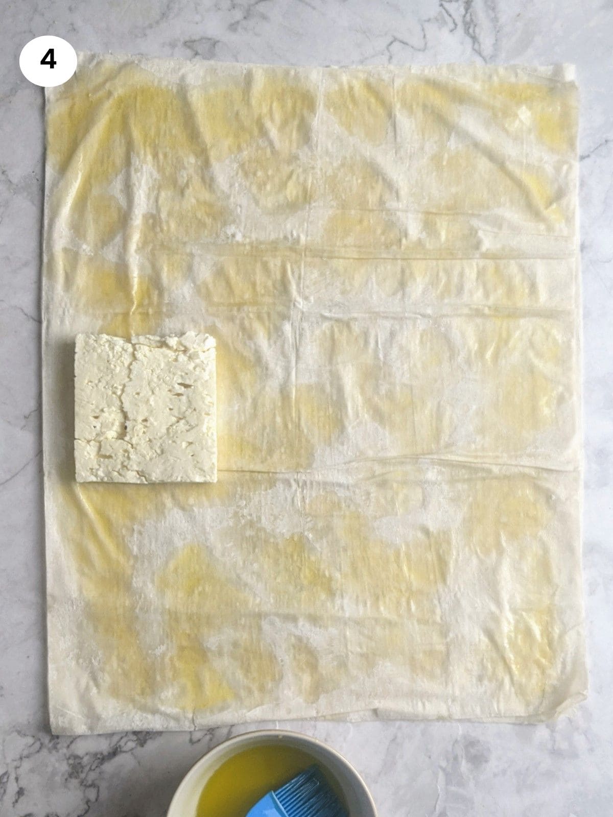 Placing the block of feta cheese at the bottom of the phyllo dough.