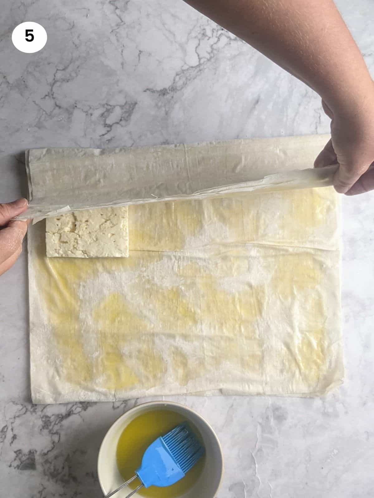 Folding the left side on top of the feta block.