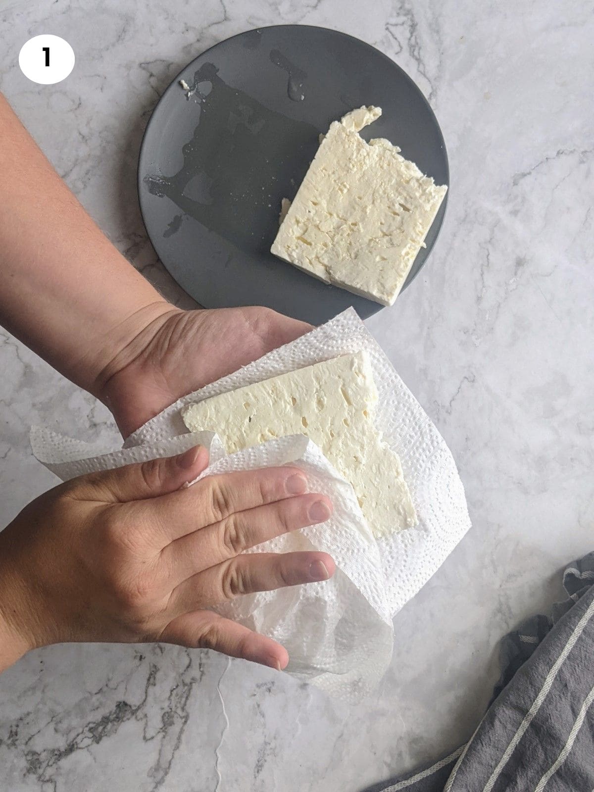 Pat drying the feta block with paper towel.