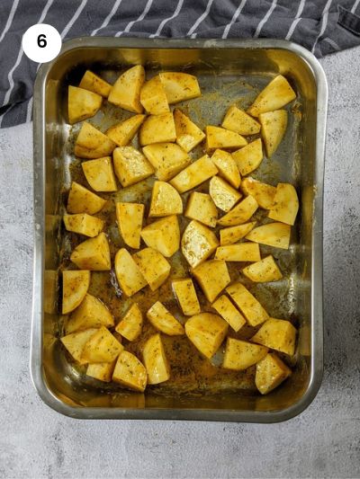 Coating the potatoes with the seasoning in a big tray.