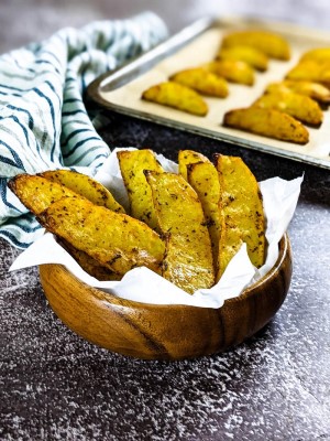 Potato wedges in a mug next to a tray