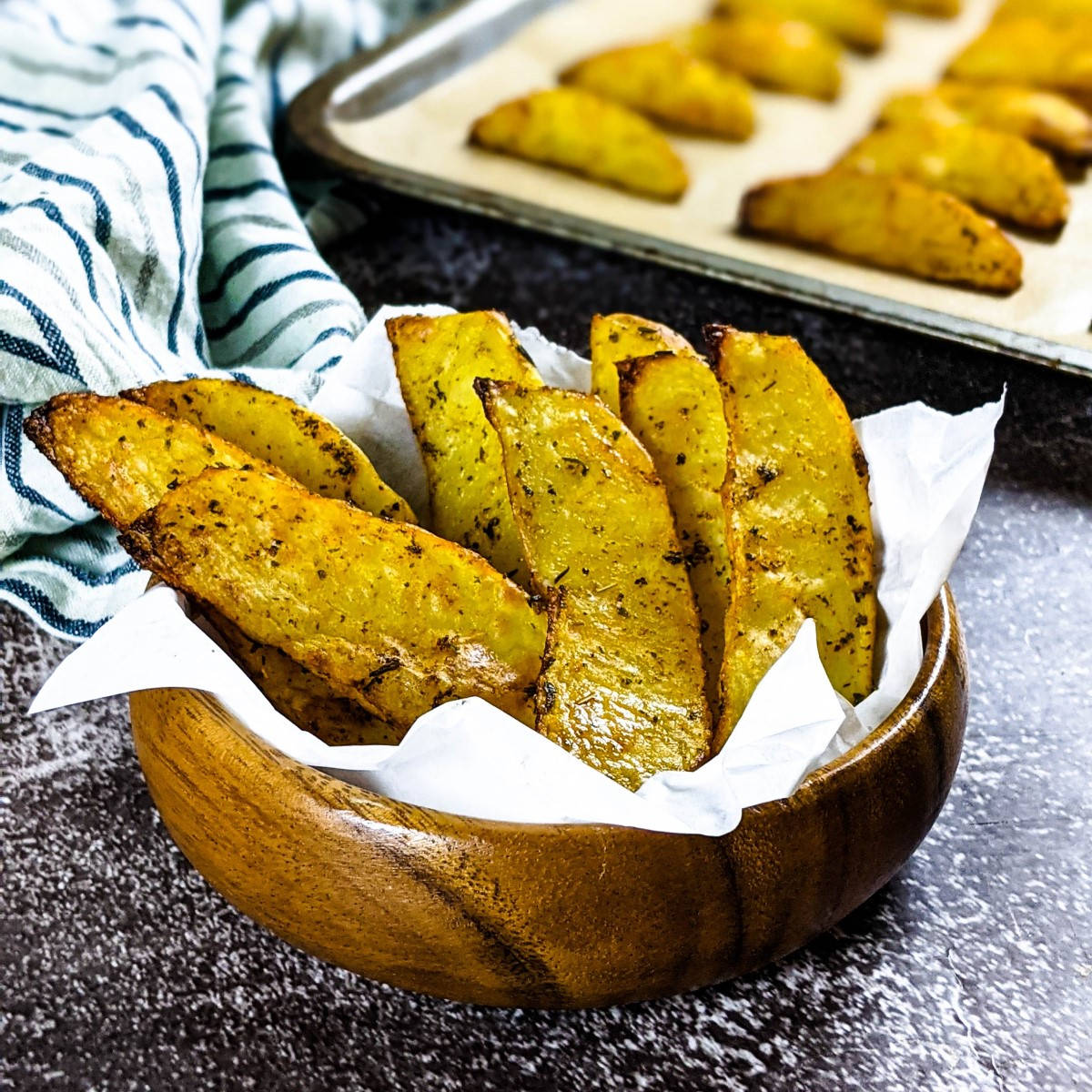 Potato wedges in a mug next to a tray