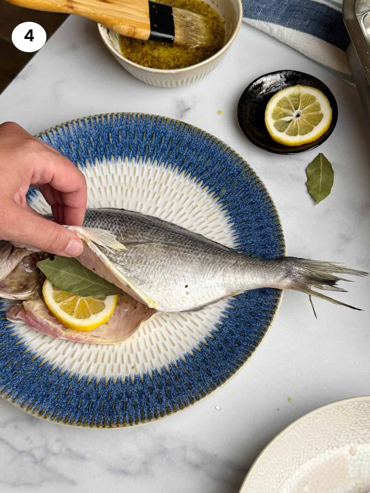 Adding a lemon slice and bay leaf to sea breams belly.