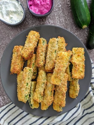 Zucchini fries on a gray plate next to bowl with yogurt dip and beetroot dip. Zucchini fries on a gray plate next to bowl with yogurt dip and beetroot dip.