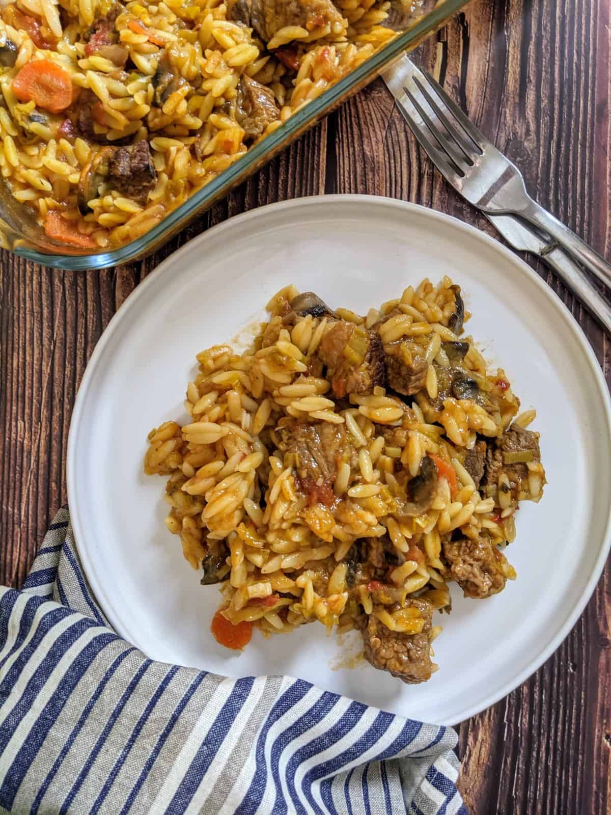 Beef & orzo pasta served on a white plate next to casserole dish