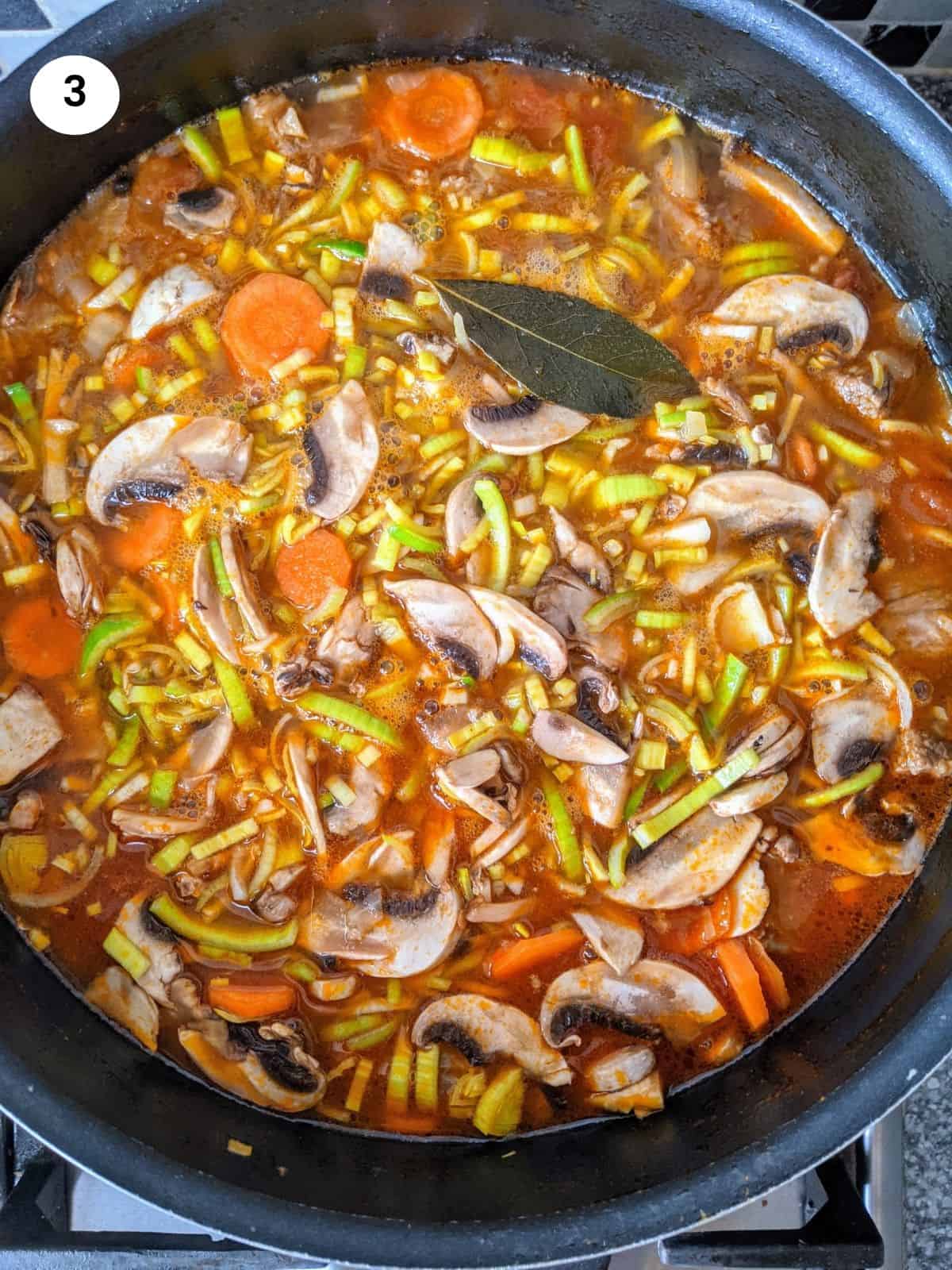 Adding chopped vegetables to the pot along with the meat.