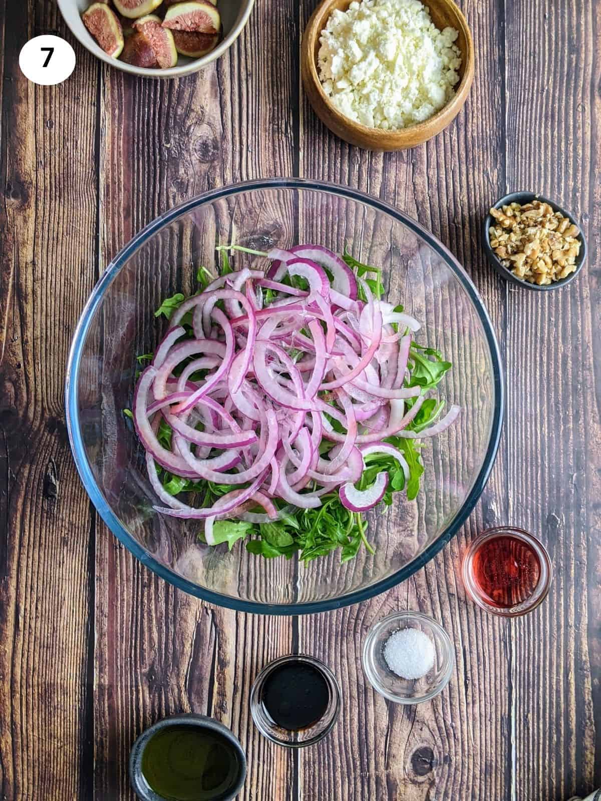 Adding the arugula and onions to a serving bowl.