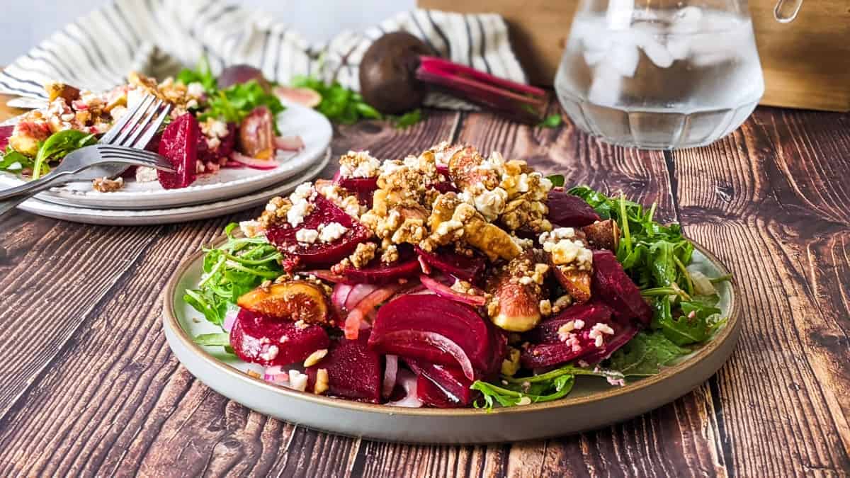 Beet and fig salad served on plate with a jug of water at the back.