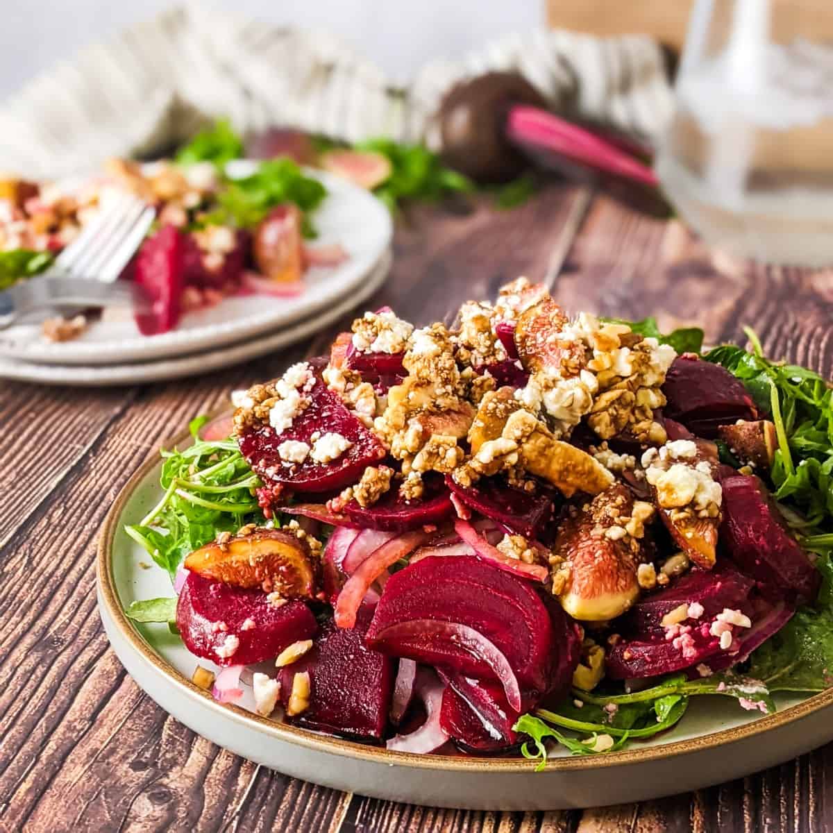 Beet and fig salad served on plate with a jug of water at the back.