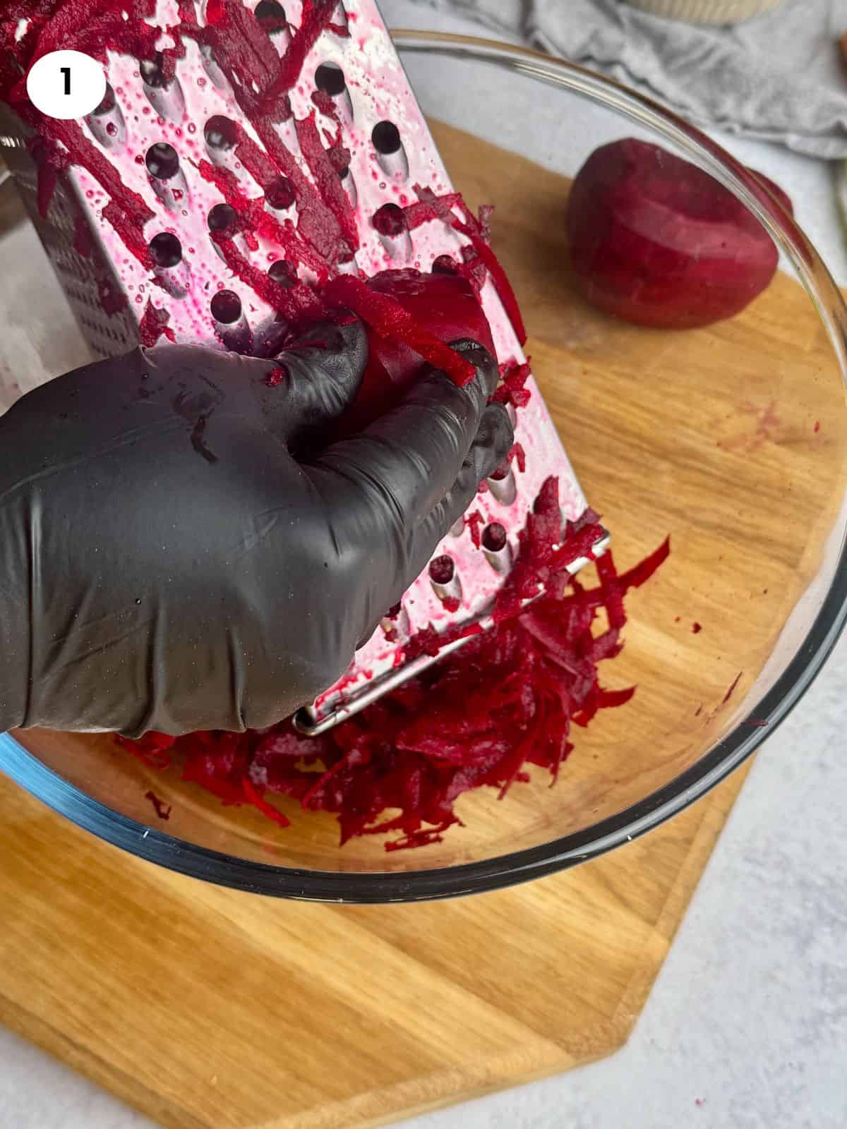 Grating beet in a glass bowl.