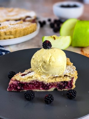 Apple Blackberry Pie slice served on gray plate with vanilla ice cream and blackberries on the side.