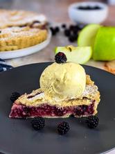 Apple Blackberry Pie slice served on gray plate with vanilla ice cream and blackberries on the side.