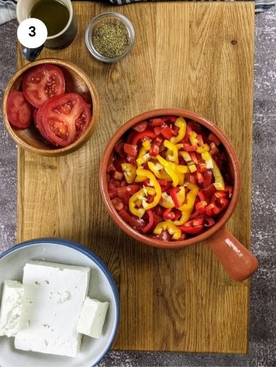 Adding the tomatoes and peppers to the ovenproof dish.