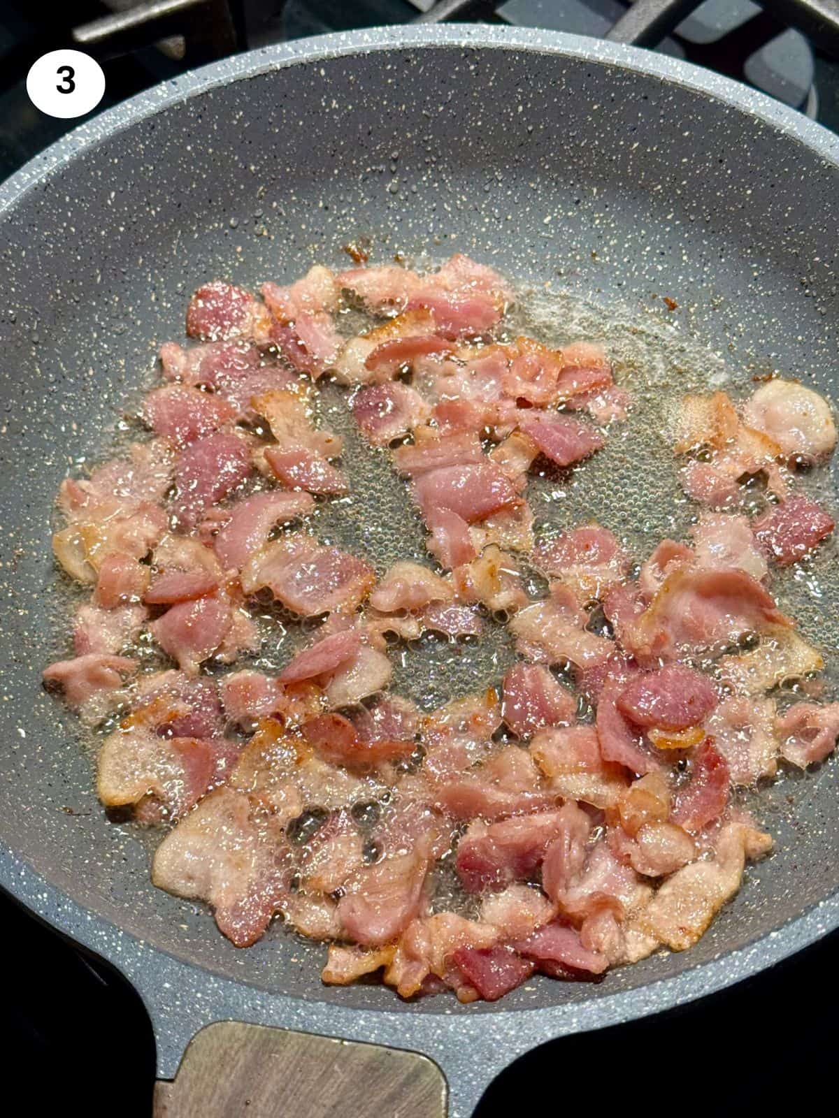 Cooking the bacon in a frying pan.