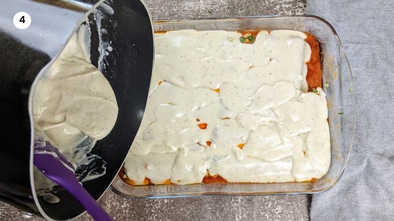 Adding the white sauce on top of the cannelloni Adding the white sauce on top of the cannelloni.