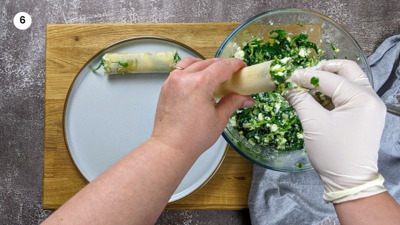 Adding the spinach and feta cheese filling to the cannelloni Adding the spinach and feta cheese filling to the cannelloni.