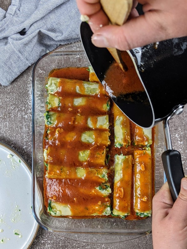 Pouring the remaining tomato sauce on top of the cannelloni.