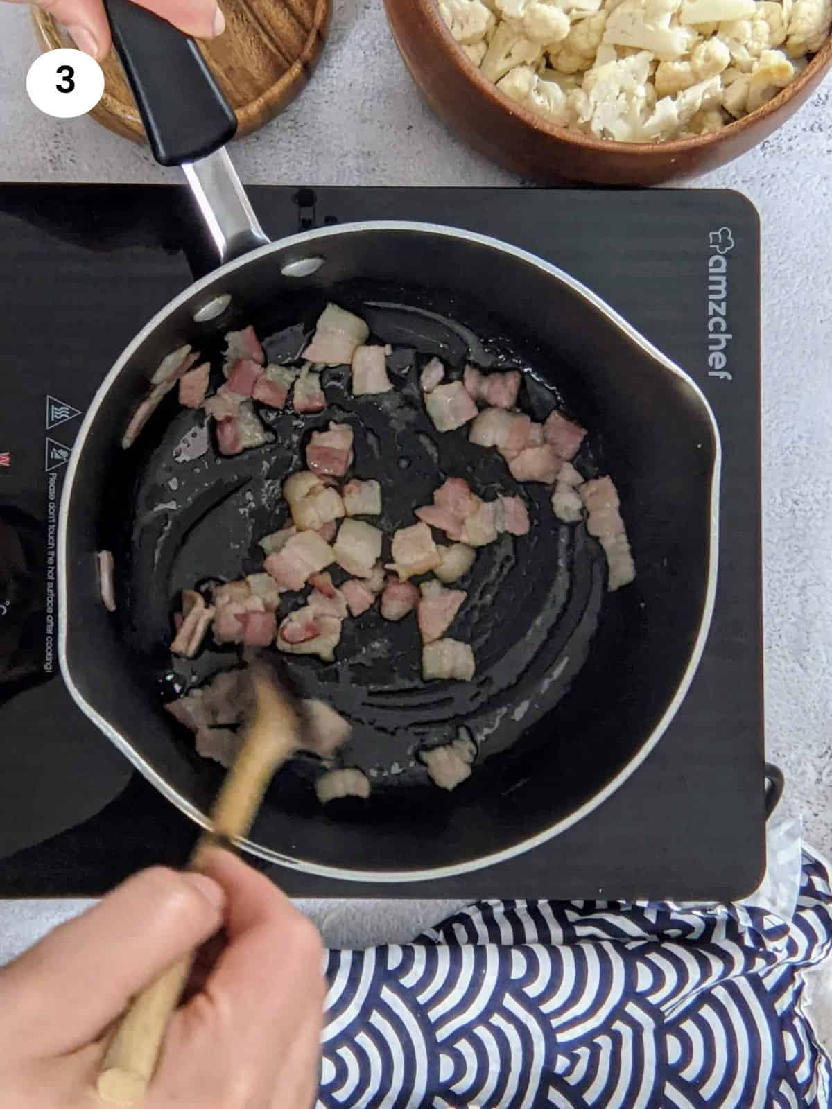 Cooking the bacon in a pan for a few minutes.