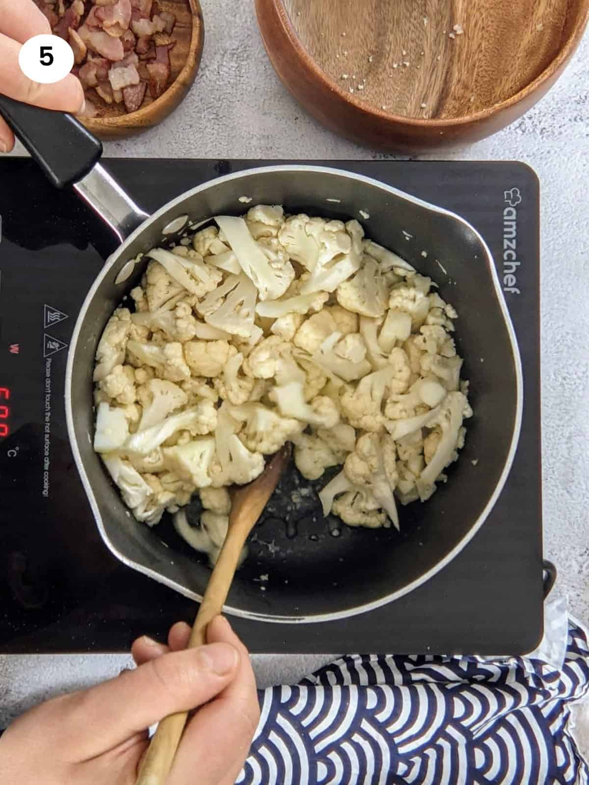 Cooking the cauliflower florets for a few minutes in the bacon grease.