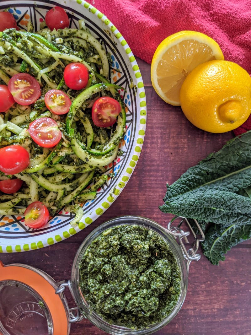 Cavolo nero pesto in a small jar and zucchini spaghetti served next to it with pesto and cherry toma