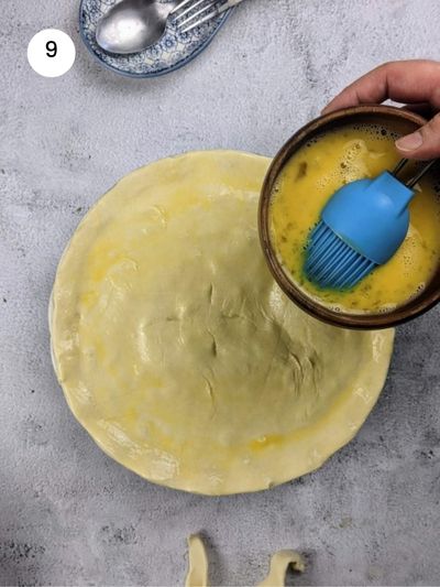 Brushing the pie with eggwash before putting it in the oven.