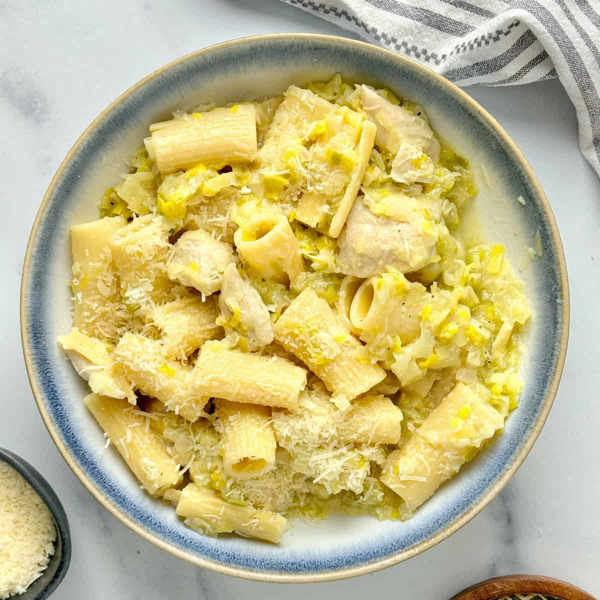 Chicken and leek pasta served in a white bowl with parmesan cheese.