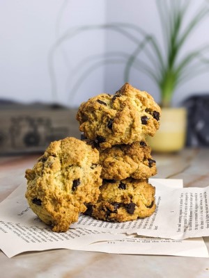Stack of three chocolate chip rock cakes on top of book pages and one on the side.