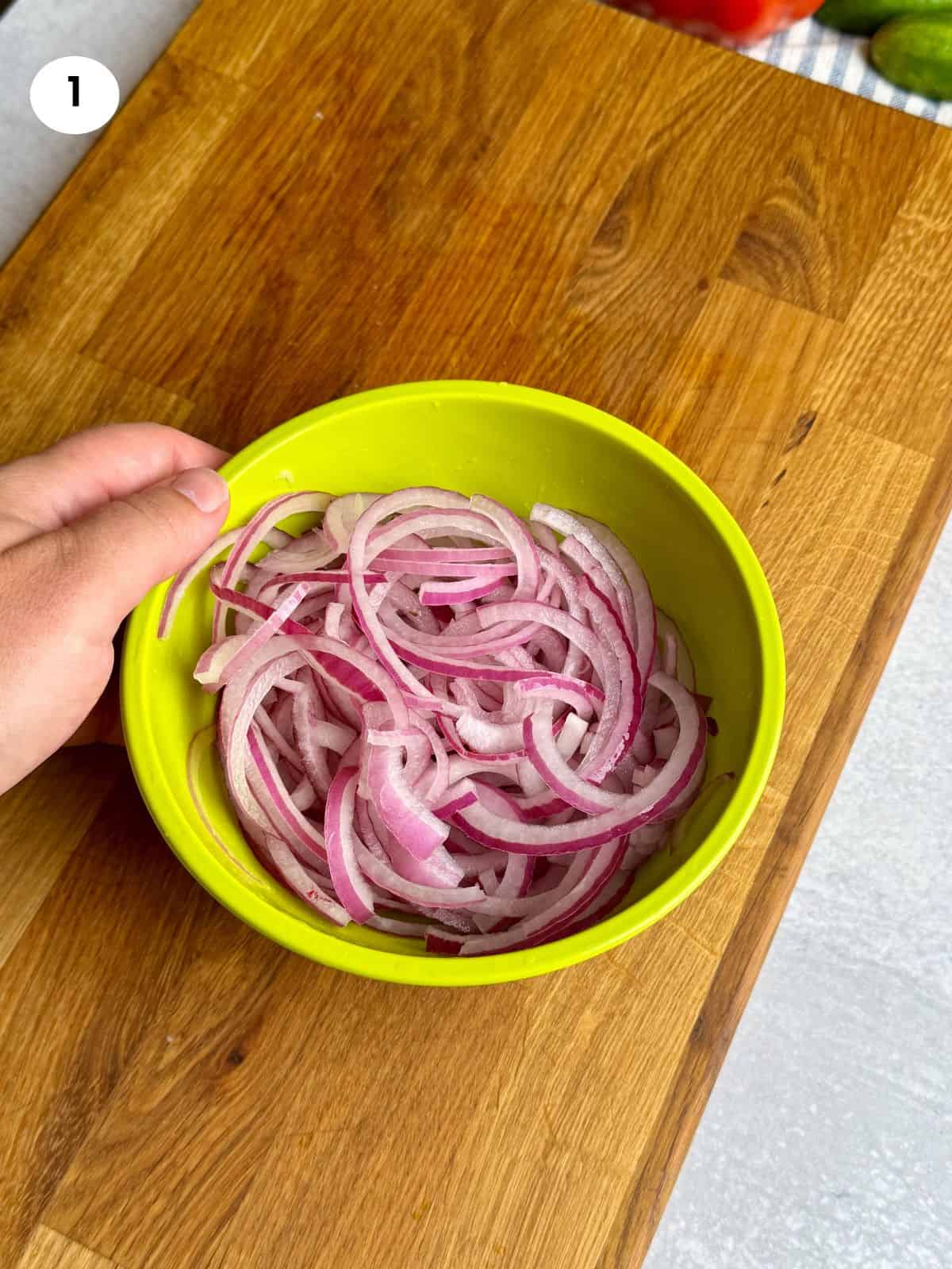 Chopped red onion in a bowl with vinegar.