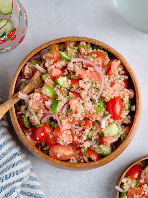 Cucumber, tomato and bulgur salad served in a wooden bowl.