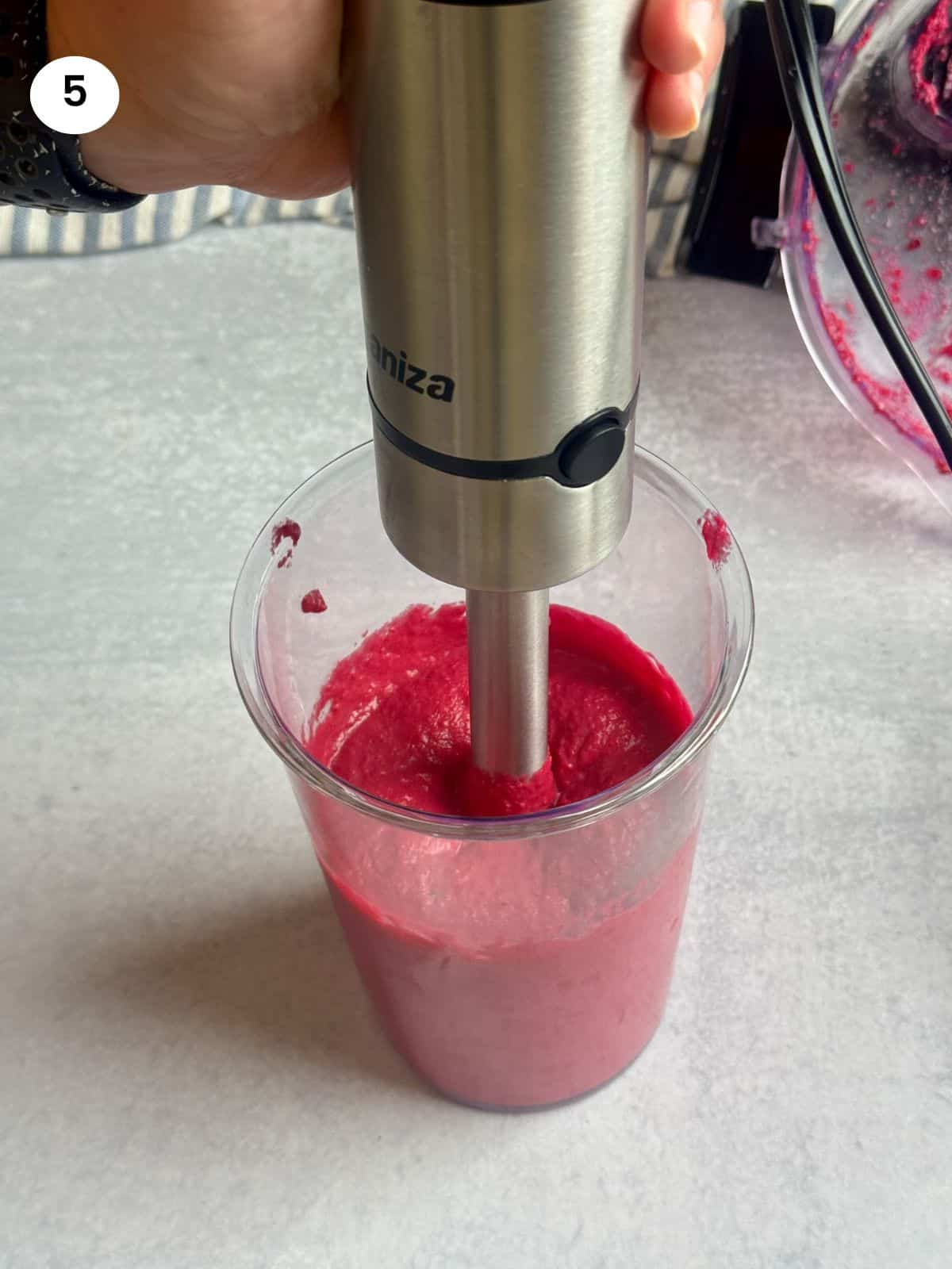 Blending the hummus with an immersion blender for a creamier result.