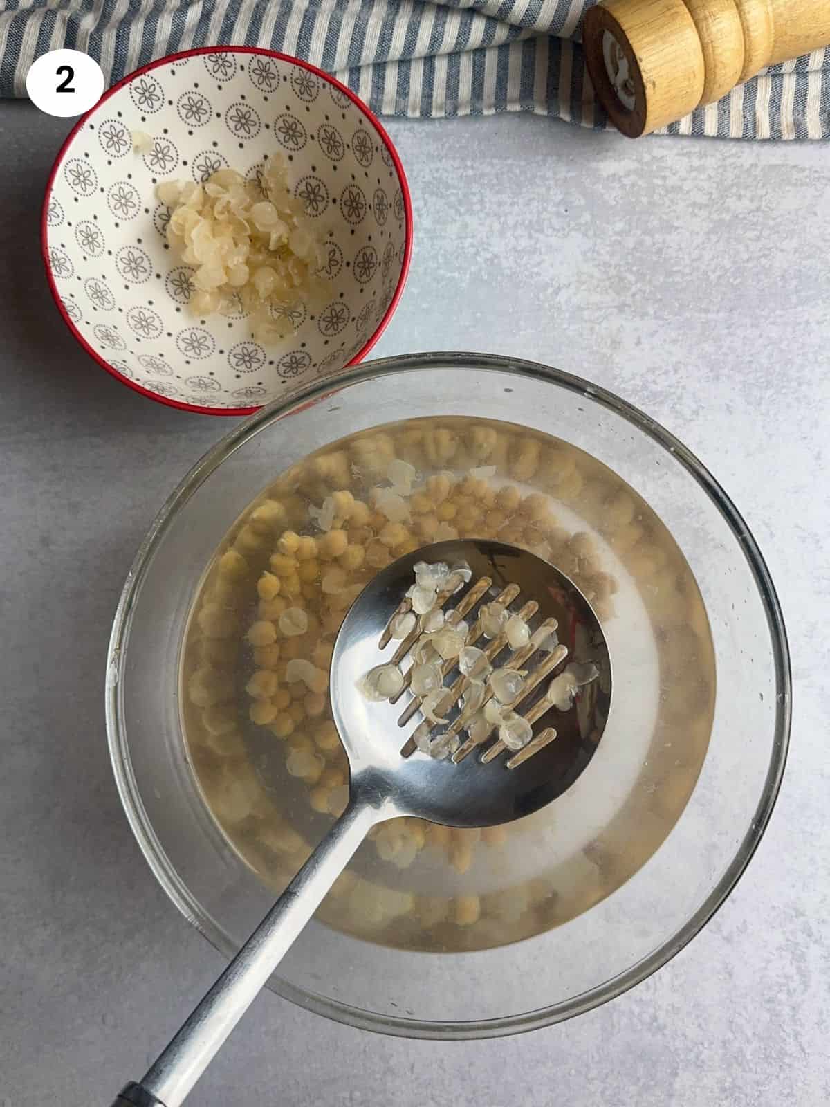 Removing the chickpeas skin with a slotted spoon.