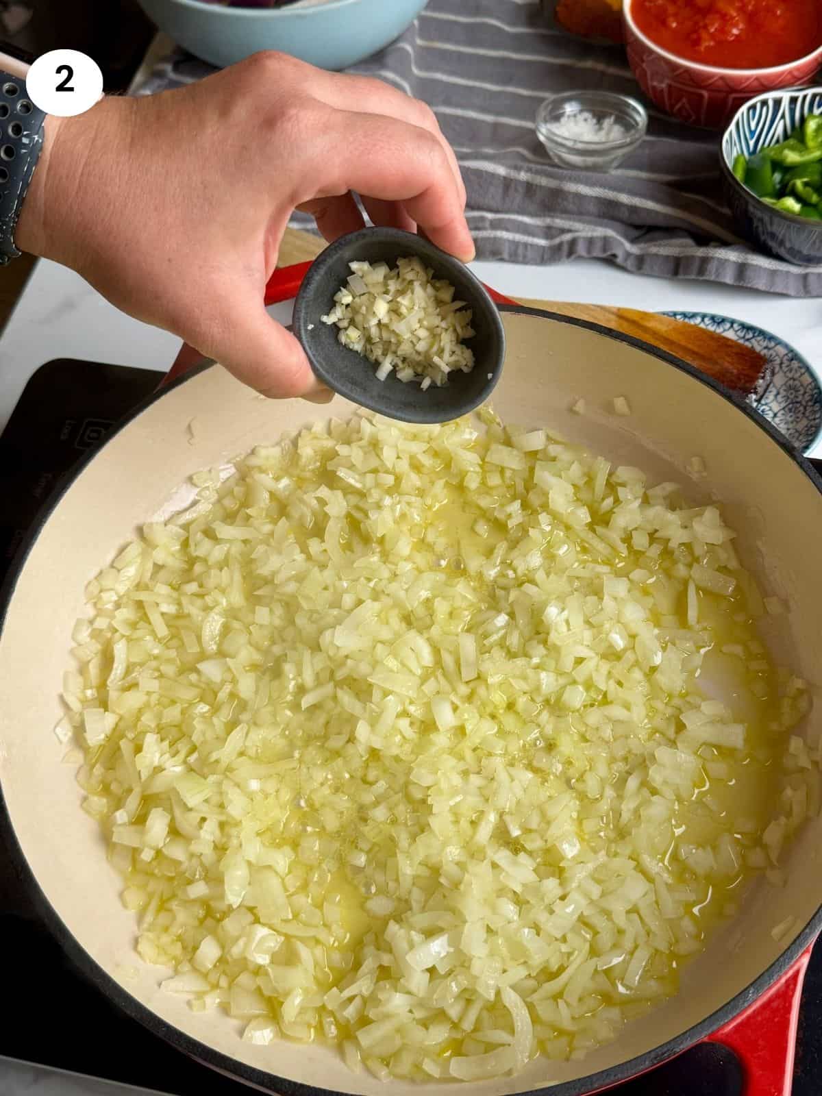 Adding the chopped garlic to the pan.