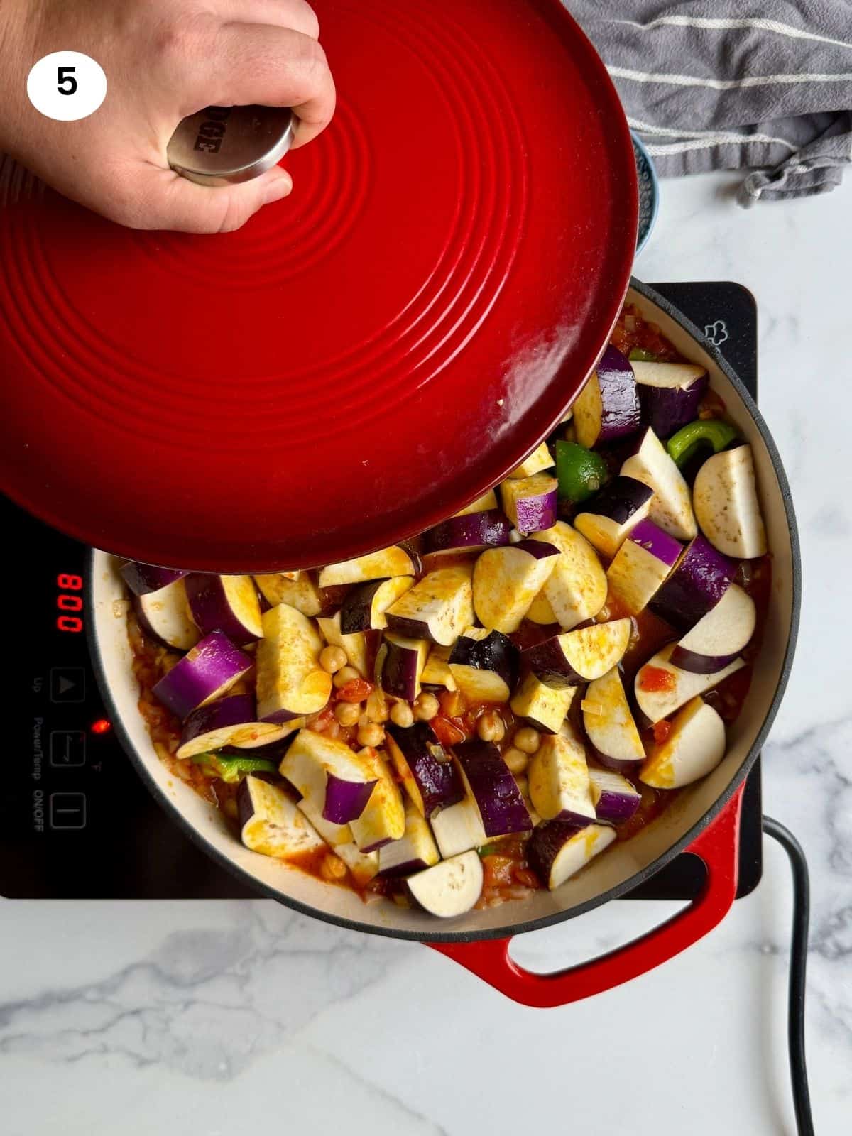 Covering the pan with the lid to simmer and cook.