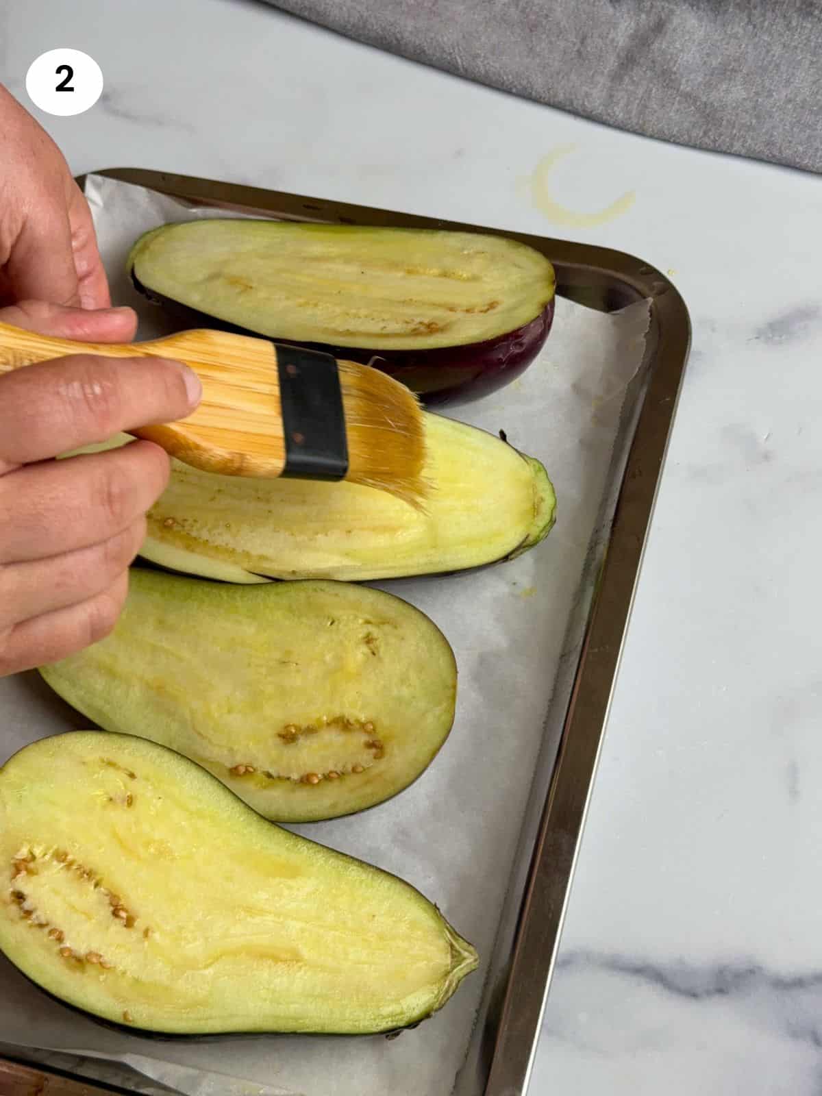 Brushing the eggplants with olive oil.