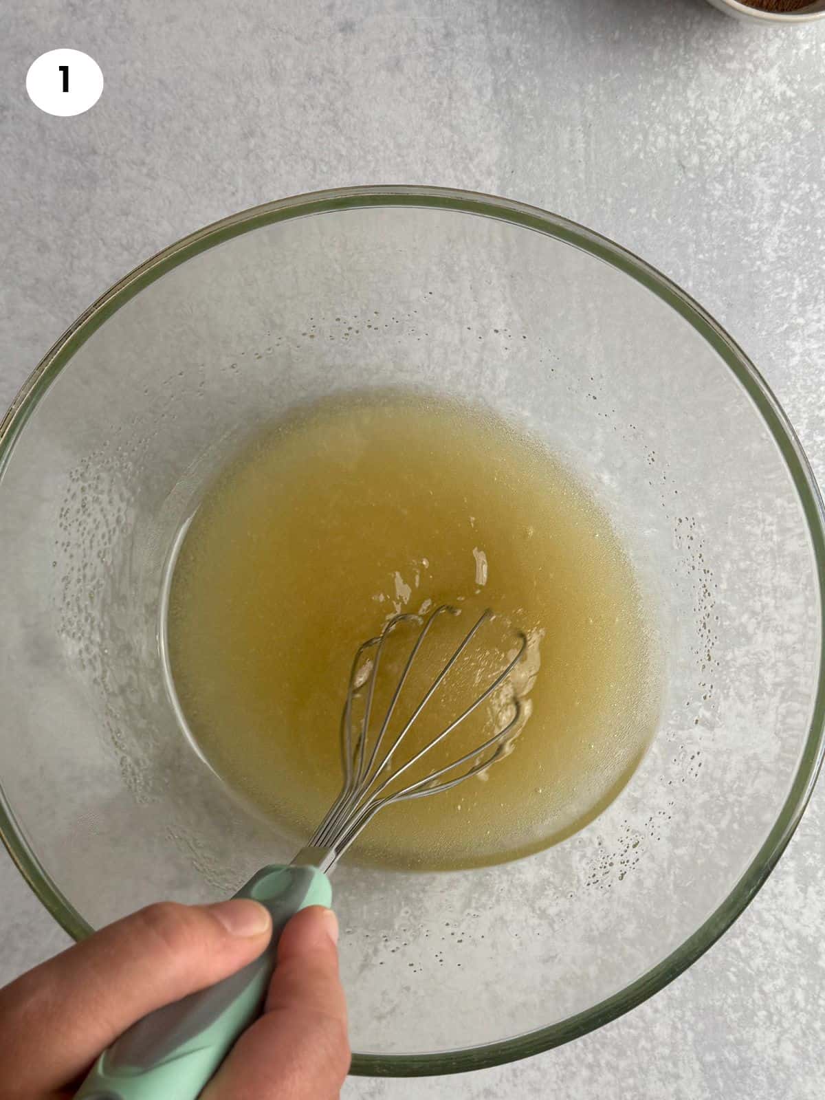 Mixing the oil and sugar in glass bowl.