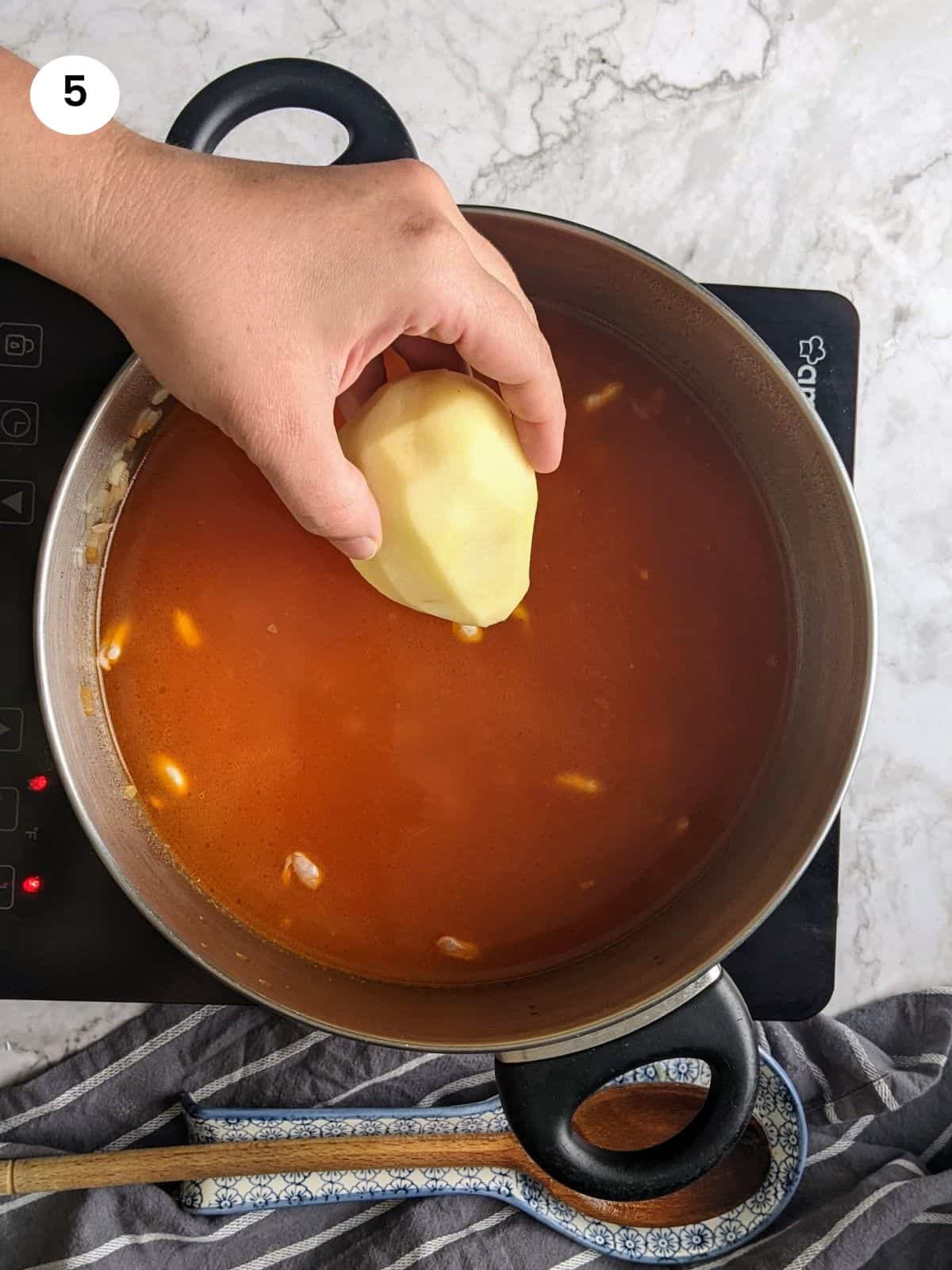 Adding spices and potato to the pot.