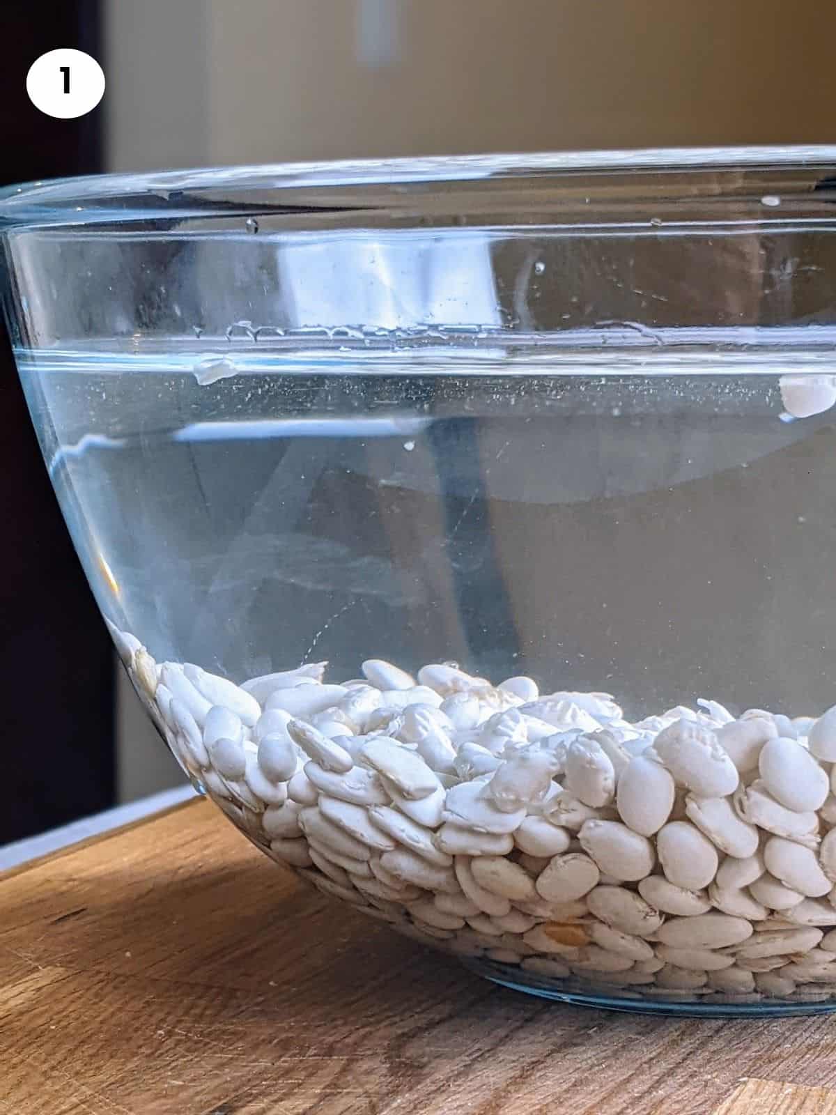 Soaking the dried white beans in a bowl full of water.